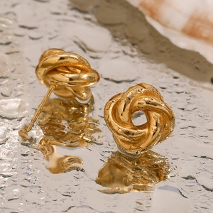 Detailed macro view of 18K gold plated earring with twisted rope knot design on mirror