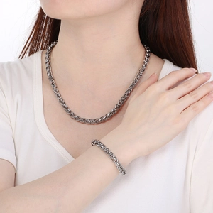 Set collana e bracciale a maglia intrecciata argento lucido su una maglietta bianca
