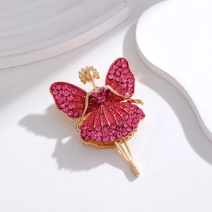 Detailed view of a red rhinestone butterfly girl brooch on a white marble background