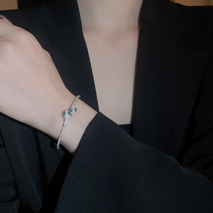 Detail of silver snake-shaped bangle with white zircons and green gemstone eyes