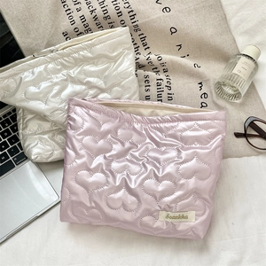 Detailed close-up of heart-quilted PU makeup bags in soft white and pastel lilac colors