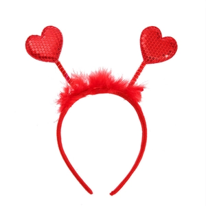 Detailed view of red sequin hearts and soft feathers on a festive party headband
