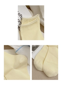 Detail view of light yellow cotton knit socks showing cuff, heel and toe stitching