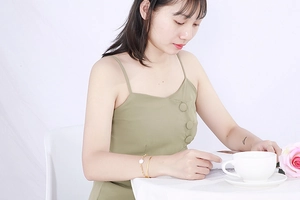 Detail of gold snake chain bracelet with flower charm and cuff on model's wrist