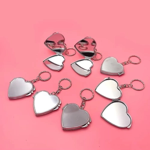 Plusieurs pendentifs miroir pliants en forme de cœur argentés avec porte-clés sur fond rose