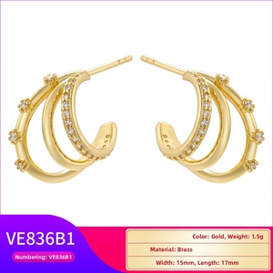 Close-up of triple-layered C-shape gold earrings with colorful zircon and brass details