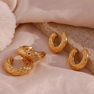 Detail of twisted spiral 18K gold plated hoop earrings on elegant silk background