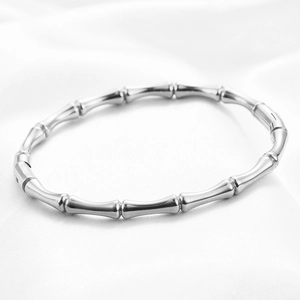 Macro shot of silver bamboo joint stainless steel bracelet on white silk background