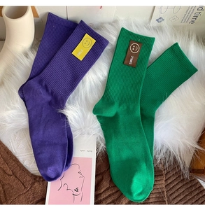 Détail de chaussettes en maille côtelée avec écussons sourire en violet et vert