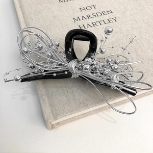 Detail of a black hair claw clip featuring intricate silver wire and bead embellishments