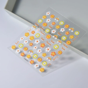Macro detail of 5D embossed sunflower and rainbow nail art stickers on a grey tray