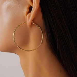 Close-up of a model wearing large golden geometric hoop earrings with polished finish