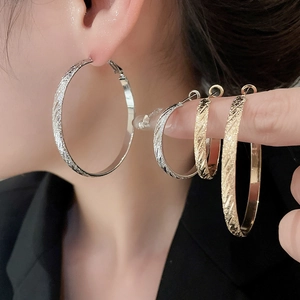 Close-up showing various sizes of gold and silver textured hoop earrings on a model