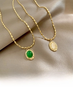 Close-up of vintage gold bamboo chain necklaces with opal and emerald green oval pendants