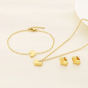Detail view of 18K gold plated heart necklace and bracelet set on a minimalist background
