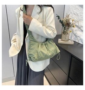 Detail view of the mint green nylon pleated shoulder bag with adjustable side drawstrings
