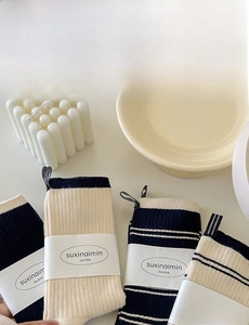 Detailed knit texture and striped patterns of mid-calf socks with paper packaging