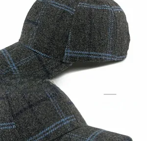 Close-up detail of dark grey plaid wool baseball cap showing fine stitching and bendable brim