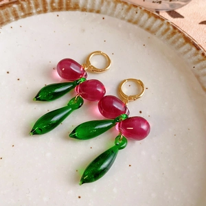 Detailed macro of crystal berry drop earrings with red and green resin beads on gold hoops