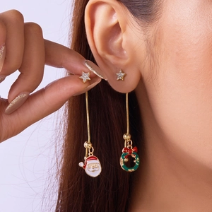 Detail view of asymmetric Christmas star earrings with Santa Claus and wreath charms