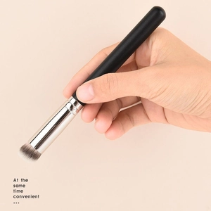 Close-up of angled concealer brush with synthetic bristles and black handle for makeup