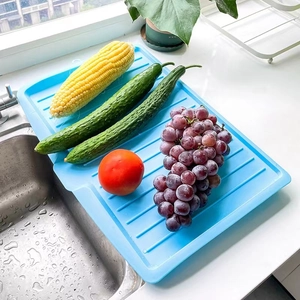 Blue plastic draining tray with vegetables and fruits placed on a kitchen counter