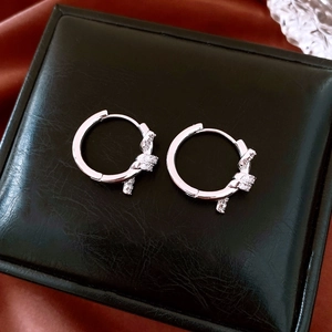 Detailed view of silver knot hoop earrings with pavé zircons on black leather texture