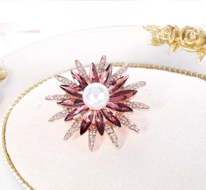 Dettaglio macro spilla fiore oro rosa con cristalli viola, perla e piccoli diamanti