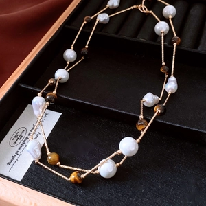 Détail de perles baroques et d'oeil de tigre sur un collier doré à double épaisseur