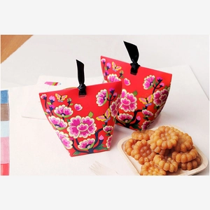 Detail of red floral folding gift box with gold butterfly prints and black ribbon handles