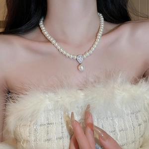 Elegant pearl necklace with diamond-encrusted teardrop pendant on female model