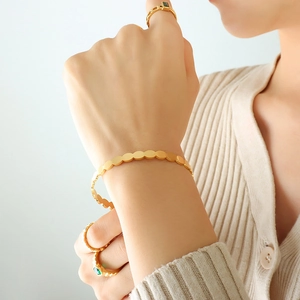 Minimalist gold plated stainless steel oval link bracelet worn on a female wrist