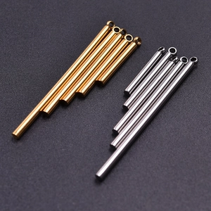 Polished gold and silver stainless steel tube pendants on dark textured background