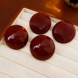 Retro burgundy red round stud earrings with smooth and textured finishes on velvet tray
