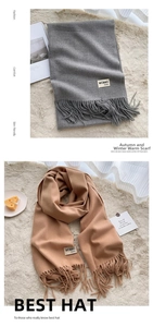 Detail of solid color scarves with tassels and brand labels on soft white rug