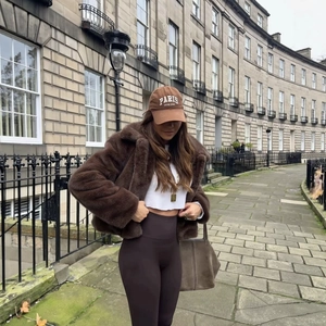 Women's faux fur jacket with large lapel styled with brown cap and tight trousers