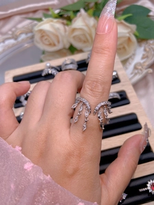 Close-up of a silver tassel ring with zircons on finger against an elegant background
