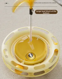 Detailed view of cat food dispenser toy with weighted base for tumbler movement and feathers