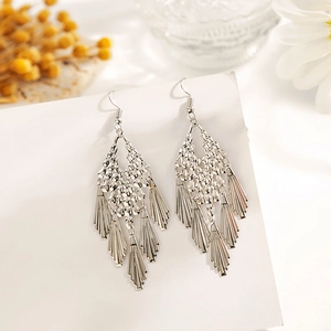 Détail de boucles d'oreilles bohèmes argentées à feuilles sur carte blanche