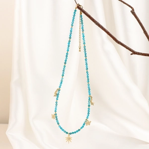 Detail of blue beaded necklace with gold butterfly pendants on an elegant branch display