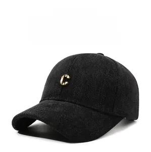 Close-up of black herringbone wool baseball cap featuring a gold metal letter C logo