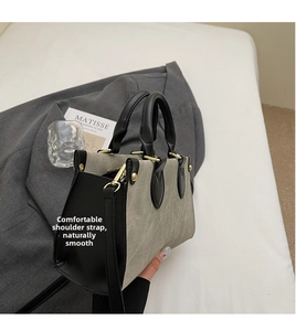 Détail du sac cabas en toile contrastée avec anses en cuir noir et boucles métalliques