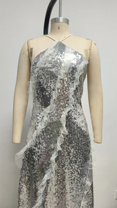 Detail of silver sequined halter dress featuring vertical white lace ruffles on bodice
