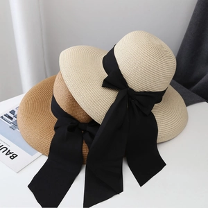 Detalle de sombreros de paja de ala ancha con elegantes cintas negras en beige y marrón