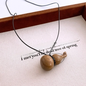 Gros plan d'un pendentif gourde en bois sculpté avec grain naturel sur un plateau beige