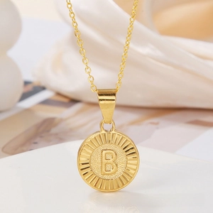 Close-up of gold round sunburst pendant with embossed letter B on a delicate chain