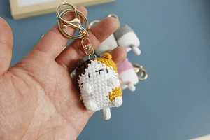 Close-up of a handmade crochet hamster keychain with golden metal ring and soft yarn details