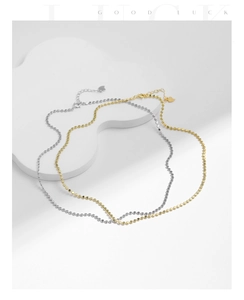 Macro detail of silver and gold bean choker necklaces with tiny heart charms