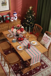 Detailed view of Christmas table runner with red and green tassels on a festive dinner table
