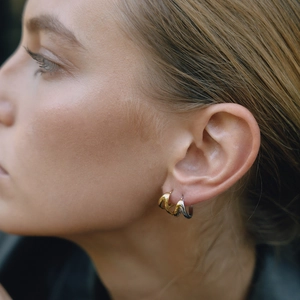Close-up of model wearing triple color high-polish 18K gold and steel hoop earrings